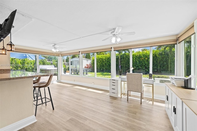 sunroom with baseboards, a wooden deck, and wood finished floors