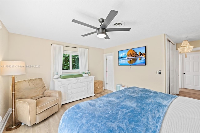 bedroom featuring baseboards, a ceiling fan, light wood finished floors, and visible vents