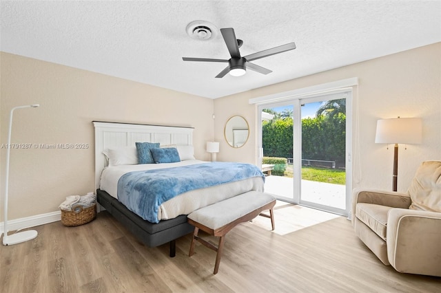 bedroom with access to outside, a textured ceiling, visible vents, and light wood-type flooring