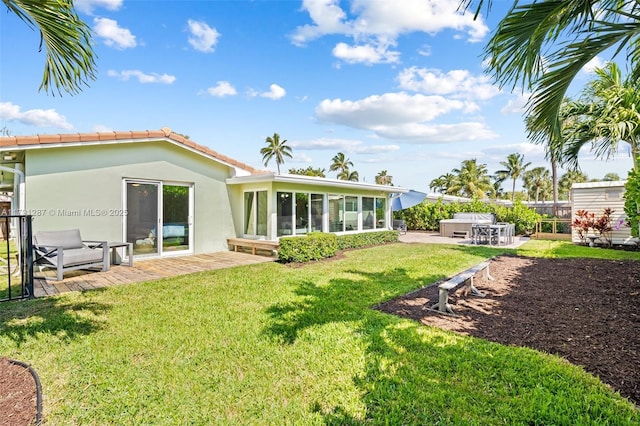 rear view of property with a patio, stucco siding, a sunroom, a lawn, and a tile roof
