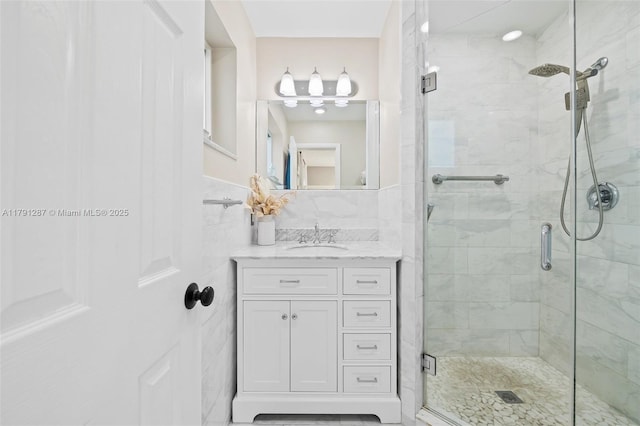 full bathroom with vanity, tile walls, and a shower stall