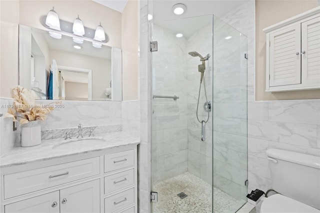 bathroom featuring vanity, tile walls, toilet, and a shower stall
