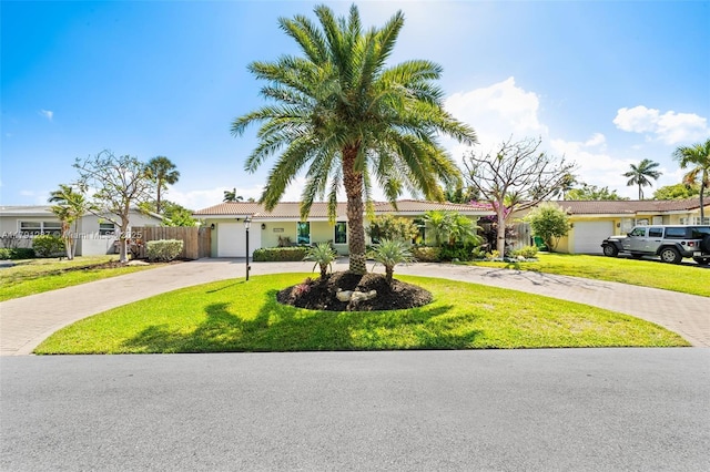 ranch-style house featuring a garage, a front lawn, fence, curved driveway, and a tiled roof