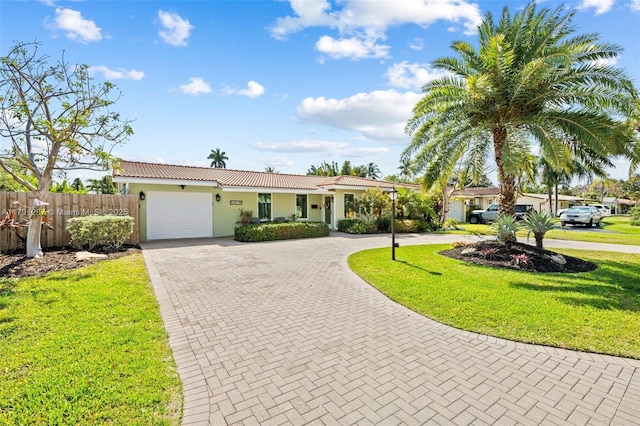 single story home with a front yard, fence, curved driveway, an attached garage, and stucco siding