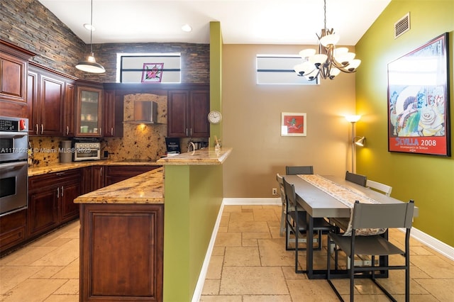 563 Lakeside Cir, Sunrise, FL 33326 - kitchen with stone tile flooring, backsplash, a chandelier, a peninsula, and wall chimney range hood