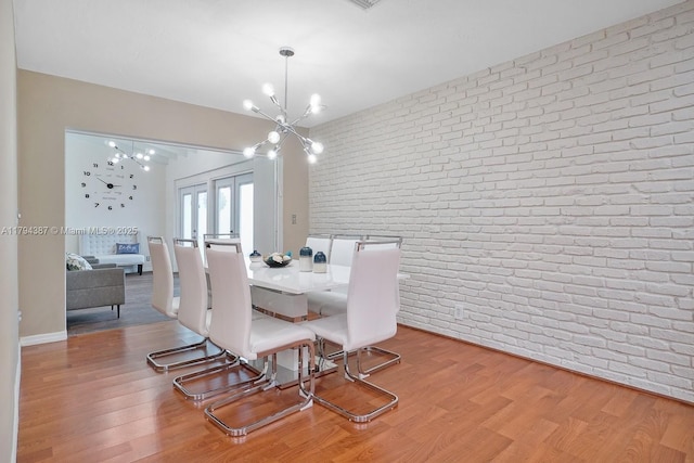 850 NE 182nd Ter, North Miami Beach, FL 33162 - dining space with brick wall, an inviting chandelier, french doors, and wood finished floors