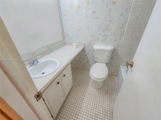 bathroom with tile patterned flooring, vanity, baseboards, toilet, and wallpapered walls