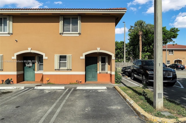 view of property featuring uncovered parking and stucco siding