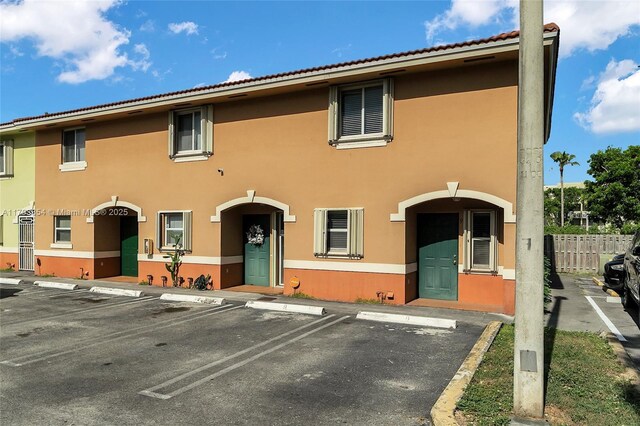 multi unit property with fence, stucco siding, and uncovered parking