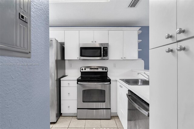 kitchen featuring visible vents, appliances with stainless steel finishes, open shelves, a sink, and light countertops