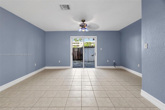 spare room with light tile patterned flooring, a textured wall, a ceiling fan, baseboards, and visible vents