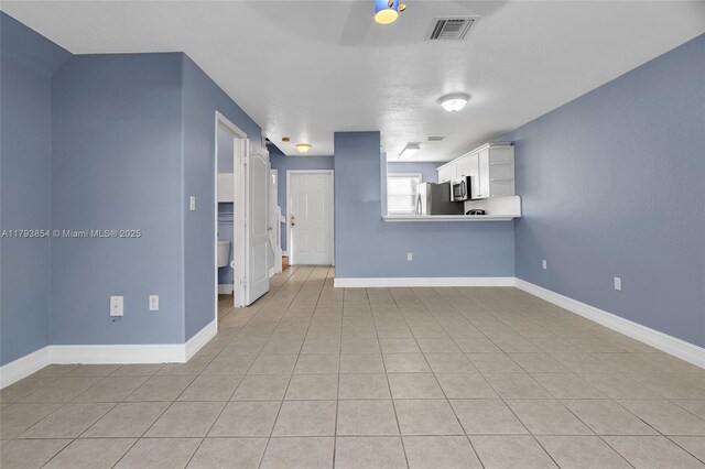 unfurnished living room with baseboards, ceiling fan, light tile patterned flooring, and visible vents