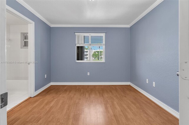 spare room with baseboards, ornamental molding, and wood finished floors