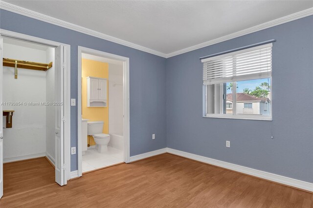 unfurnished bedroom with baseboards, ornamental molding, a closet, and wood finished floors