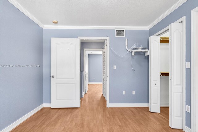 unfurnished bedroom with baseboards, visible vents, ornamental molding, and light wood-type flooring