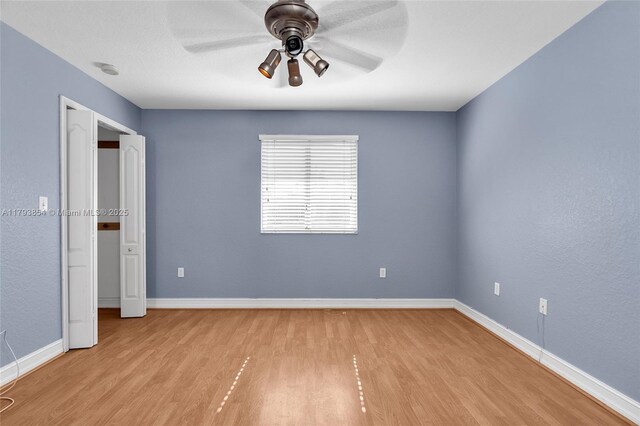 unfurnished bedroom featuring baseboards, light wood finished floors, and ceiling fan