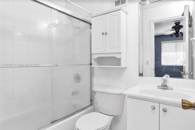 bathroom with toilet, visible vents, combined bath / shower with glass door, and vanity