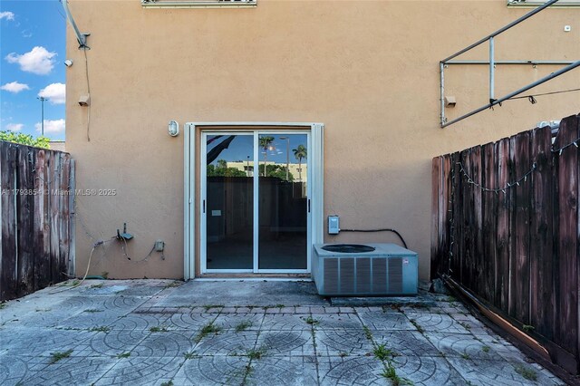 view of exterior entry featuring fence, stucco siding, and a patio area