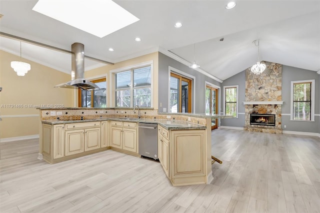 kitchen featuring cream cabinets, dishwasher, light wood-style flooring, open floor plan, and baseboards