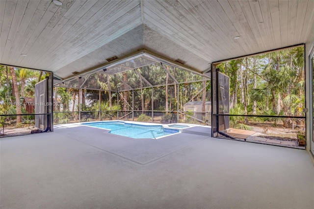 view of swimming pool featuring glass enclosure, a pool with connected hot tub, and a patio area