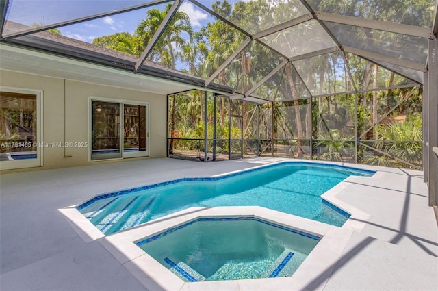 pool with a patio, glass enclosure, and an in ground hot tub