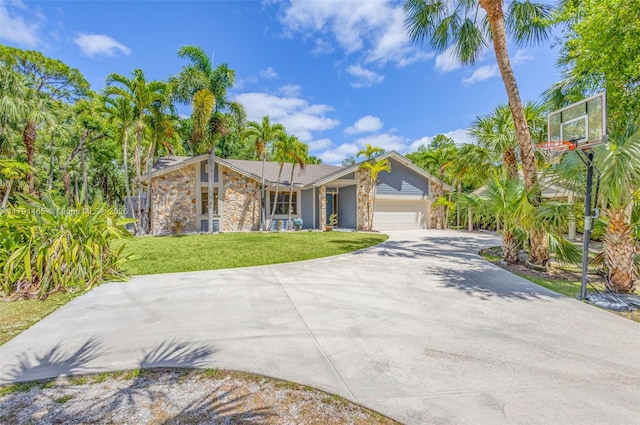 view of front facade with a garage, concrete driveway, a front lawn, and stone siding