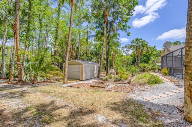 view of yard featuring a detached garage, a storage unit, an outbuilding, and glass enclosure