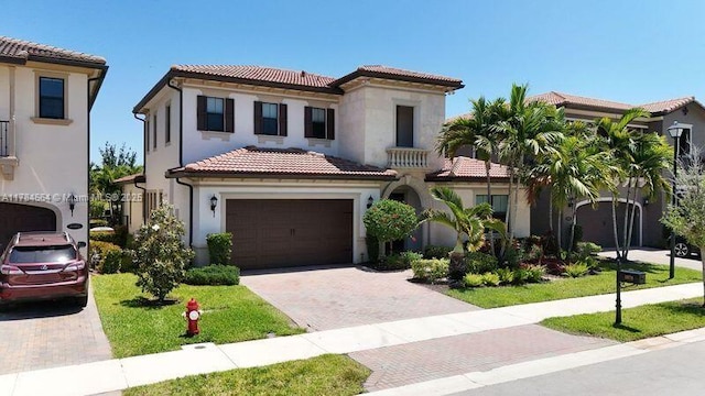 mediterranean / spanish-style home with a tiled roof, decorative driveway, stucco siding, and a garage