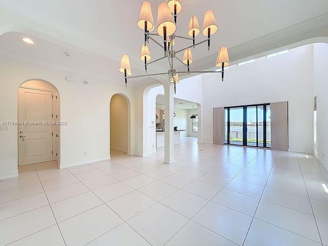 unfurnished room with light tile patterned floors, arched walkways, baseboards, and recessed lighting