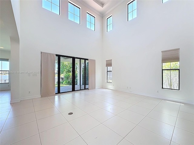 tiled empty room with a high ceiling and a healthy amount of sunlight