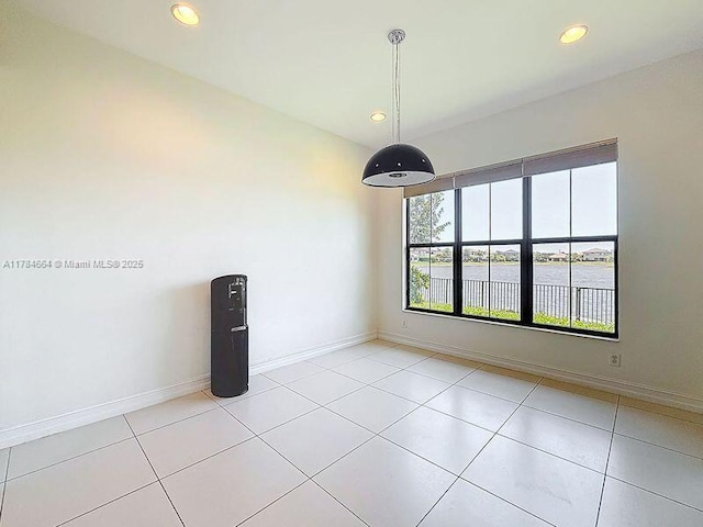 unfurnished dining area with baseboards, tile patterned flooring, a water view, and recessed lighting