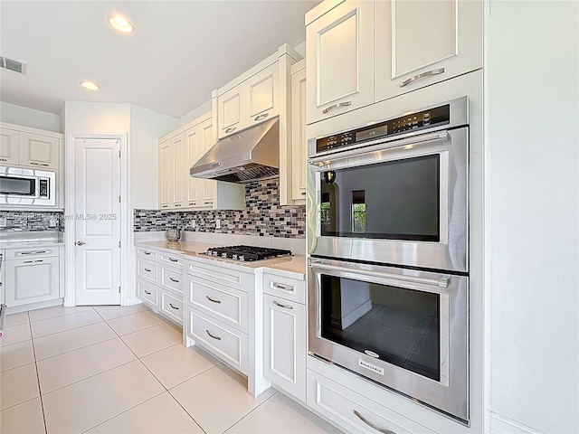 kitchen with decorative backsplash, visible vents, light countertops, under cabinet range hood, and stainless steel appliances