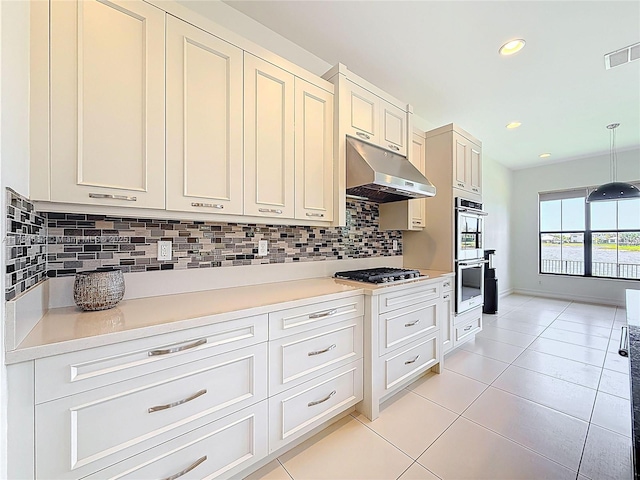 kitchen featuring under cabinet range hood, stainless steel appliances, visible vents, and backsplash
