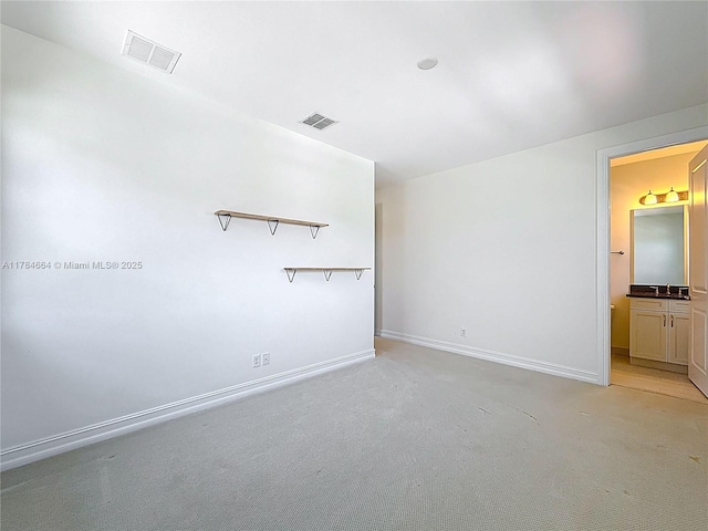spare room with light colored carpet, baseboards, visible vents, and a sink