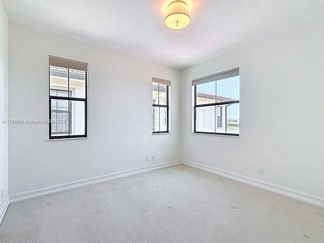 spare room with carpet floors, baseboards, and plenty of natural light