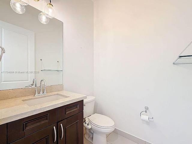 bathroom with vanity, tile patterned flooring, baseboards, and toilet