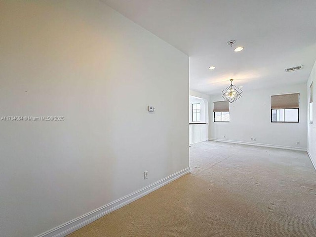 spare room featuring light carpet, a chandelier, recessed lighting, baseboards, and visible vents