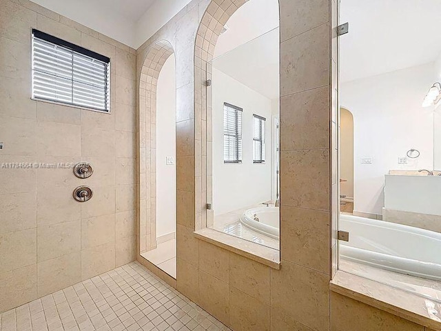 bathroom with tile patterned flooring, a tile shower, a bath, and vanity