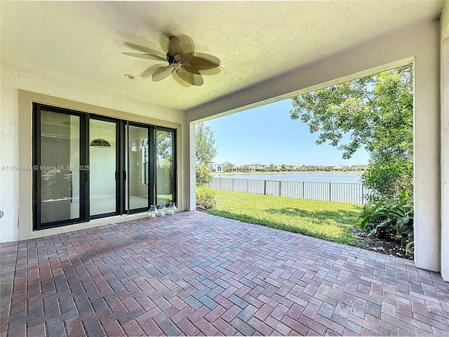 view of patio featuring a water view, ceiling fan, and fence