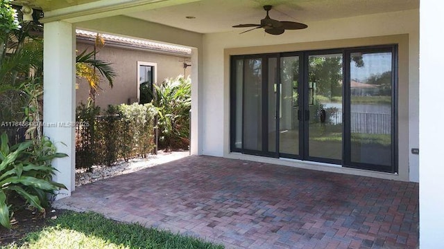entrance to property with french doors, a ceiling fan, a patio area, and stucco siding