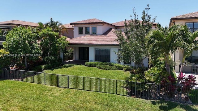 mediterranean / spanish house with a fenced backyard, stucco siding, a front lawn, and a tile roof