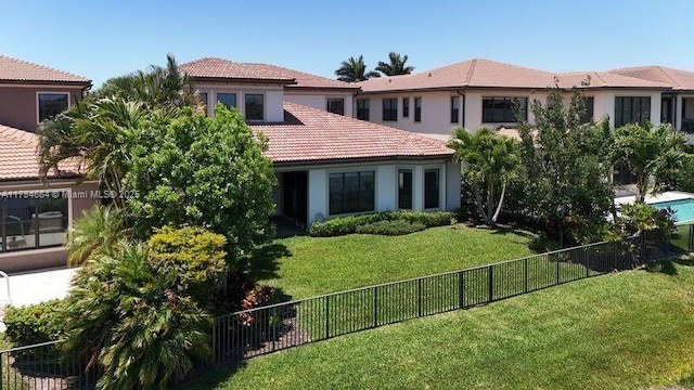 view of front of house featuring a fenced backyard, stucco siding, a tile roof, and a front yard