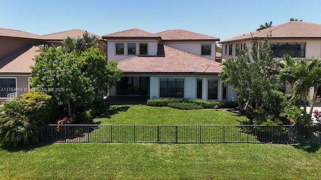 rear view of house featuring a fenced backyard, a tiled roof, a yard, and stucco siding