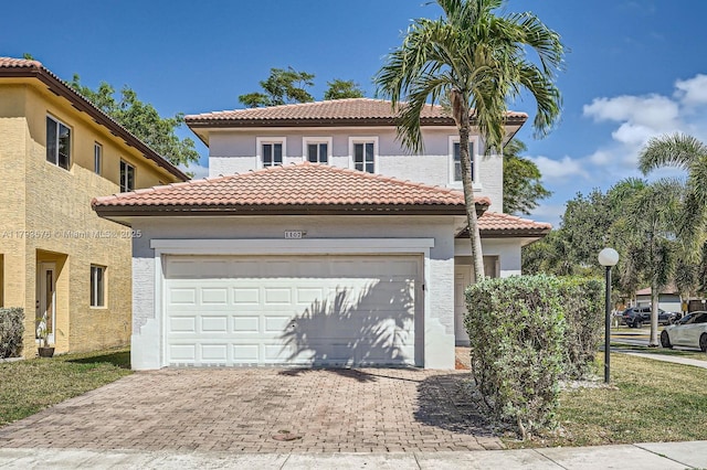 mediterranean / spanish-style home with stucco siding, driveway, a tile roof, and a garage