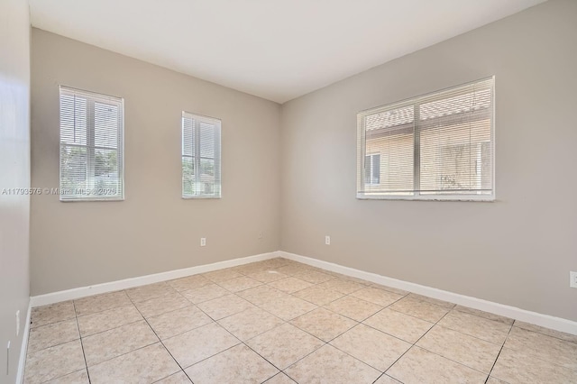 spare room featuring baseboards and light tile patterned floors