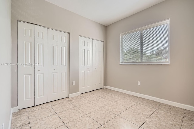 1107 NE 41st Ave, Homestead, FL 33033 - unfurnished bedroom featuring baseboards, multiple closets, and light tile patterned floors