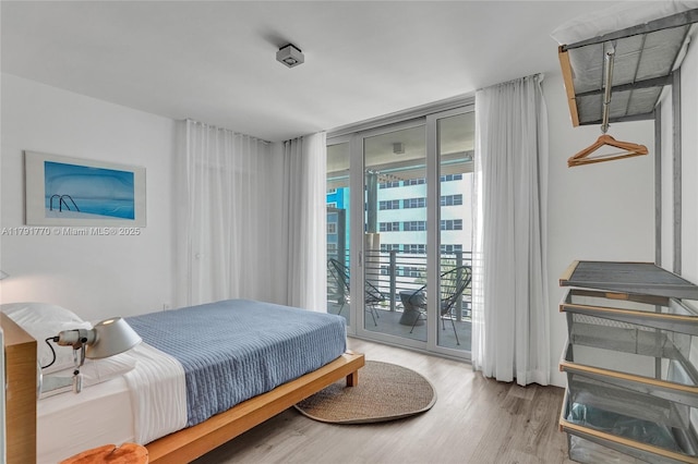 bedroom with a wall of windows, access to outside, and wood finished floors