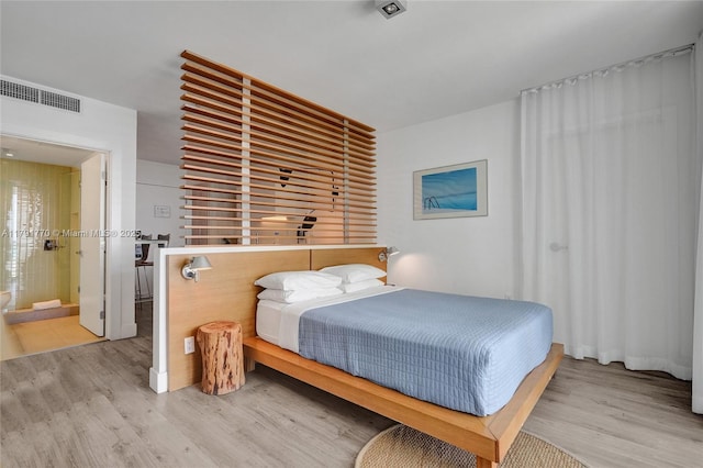 bedroom featuring ensuite bath, light wood-style flooring, and visible vents
