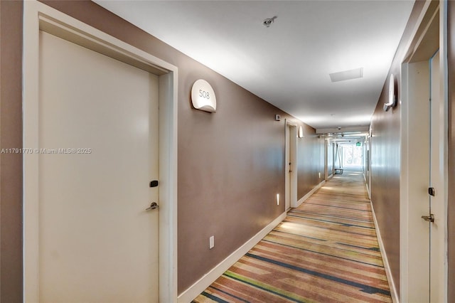 hallway featuring light carpet and baseboards