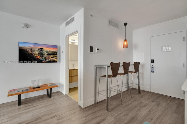 foyer entrance featuring baseboards, visible vents, and wood finished floors